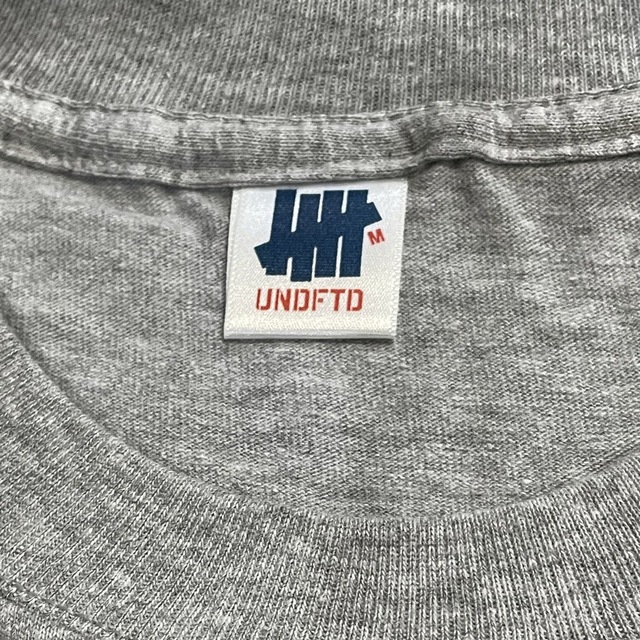 UNDEFEATED(アンディフィーテッド)の【UNDEFEATED】ビッグロゴ Tシャツ M グレー 新品 アンディー メンズのトップス(Tシャツ/カットソー(半袖/袖なし))の商品写真