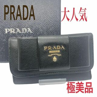 プラダ(PRADA)の【極美品】PRADA キーケース　リボン　メタルロゴ　レザー　箱付　黒(キーケース)