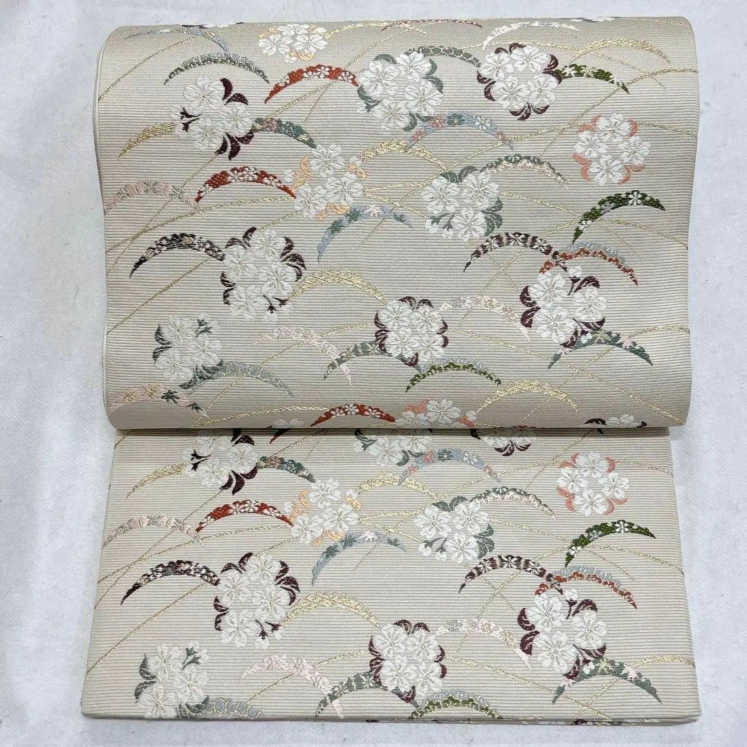 素材正絹商品番号ベージュ地に色とりどりの芝草文や桜の刺繍があしらわれた袋帯　着物