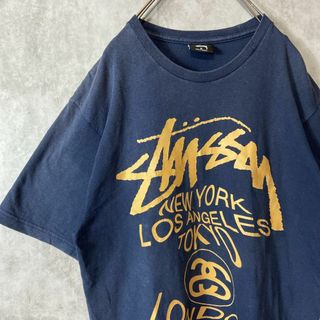 ステューシー(STUSSY)の【メキシコ製、ワールドツアーロゴ】stussy両目プリント古着ストリート変形M(Tシャツ/カットソー(半袖/袖なし))