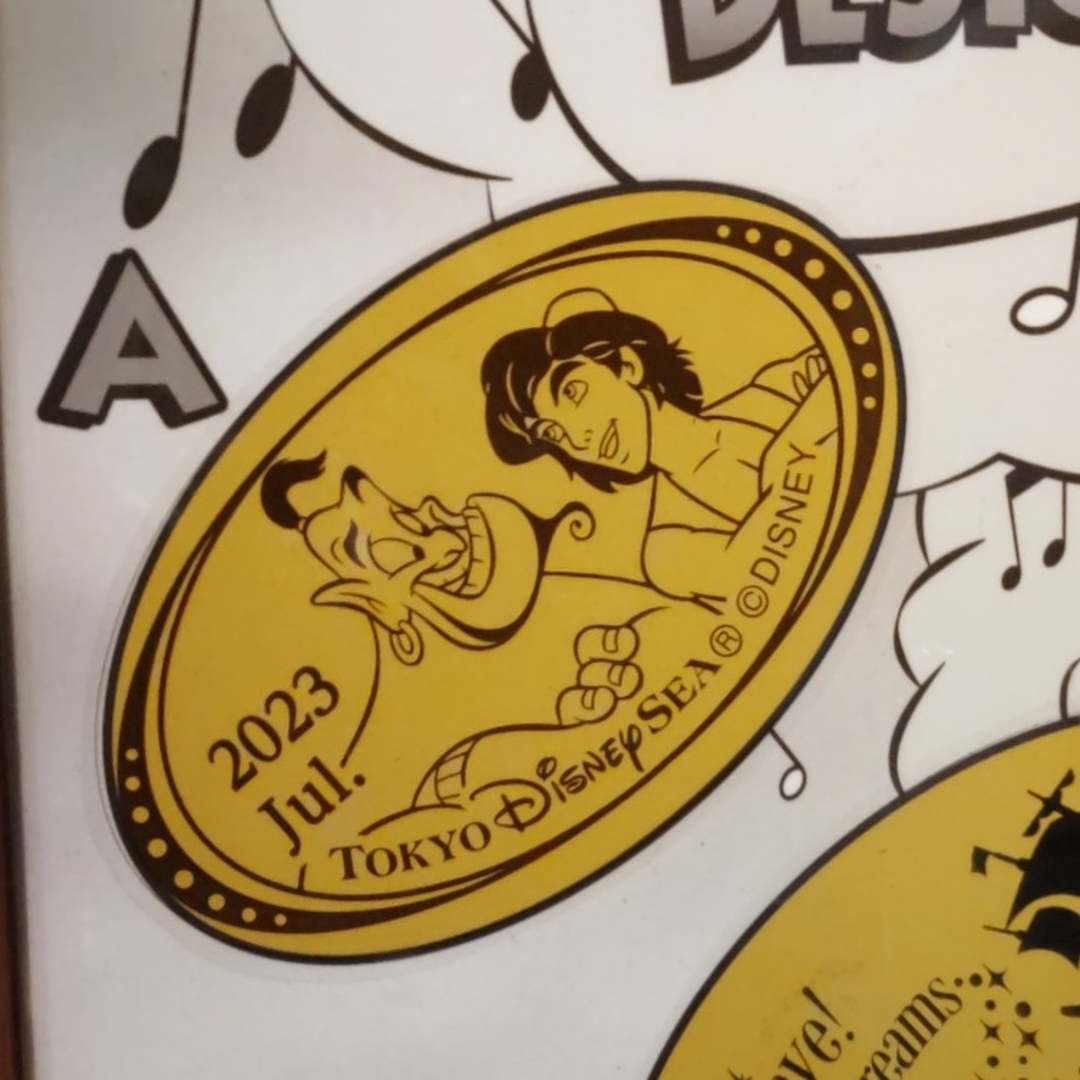 Disney(ディズニー)のTDS 2023年7月のマンスリースーベニアメダル アラジンとジーニー エンタメ/ホビーのおもちゃ/ぬいぐるみ(キャラクターグッズ)の商品写真