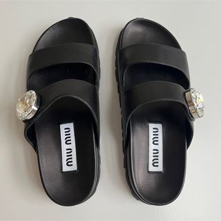 ミュウミュウ(miumiu)のmiumiu ビジューつき レザー調サンダル ブラック 23cm(サンダル)